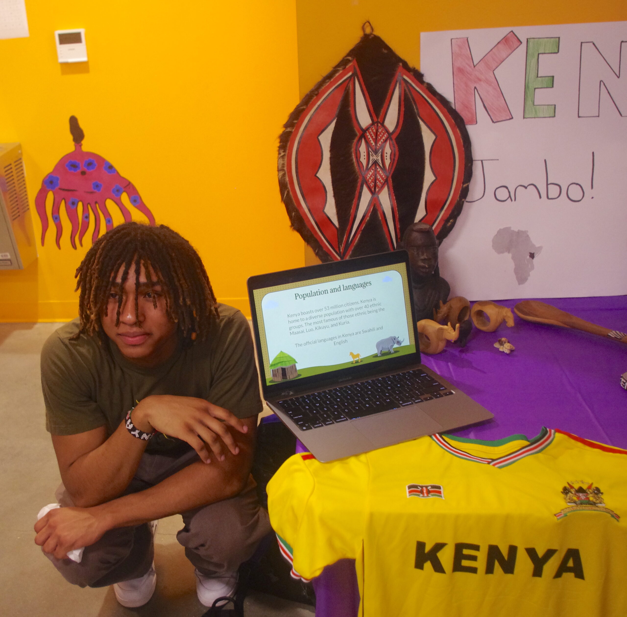 Student squatting next to his culture display