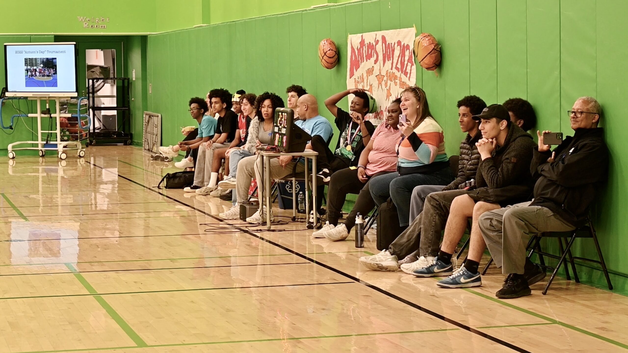 The audience sitting against the wall watching the basketball games