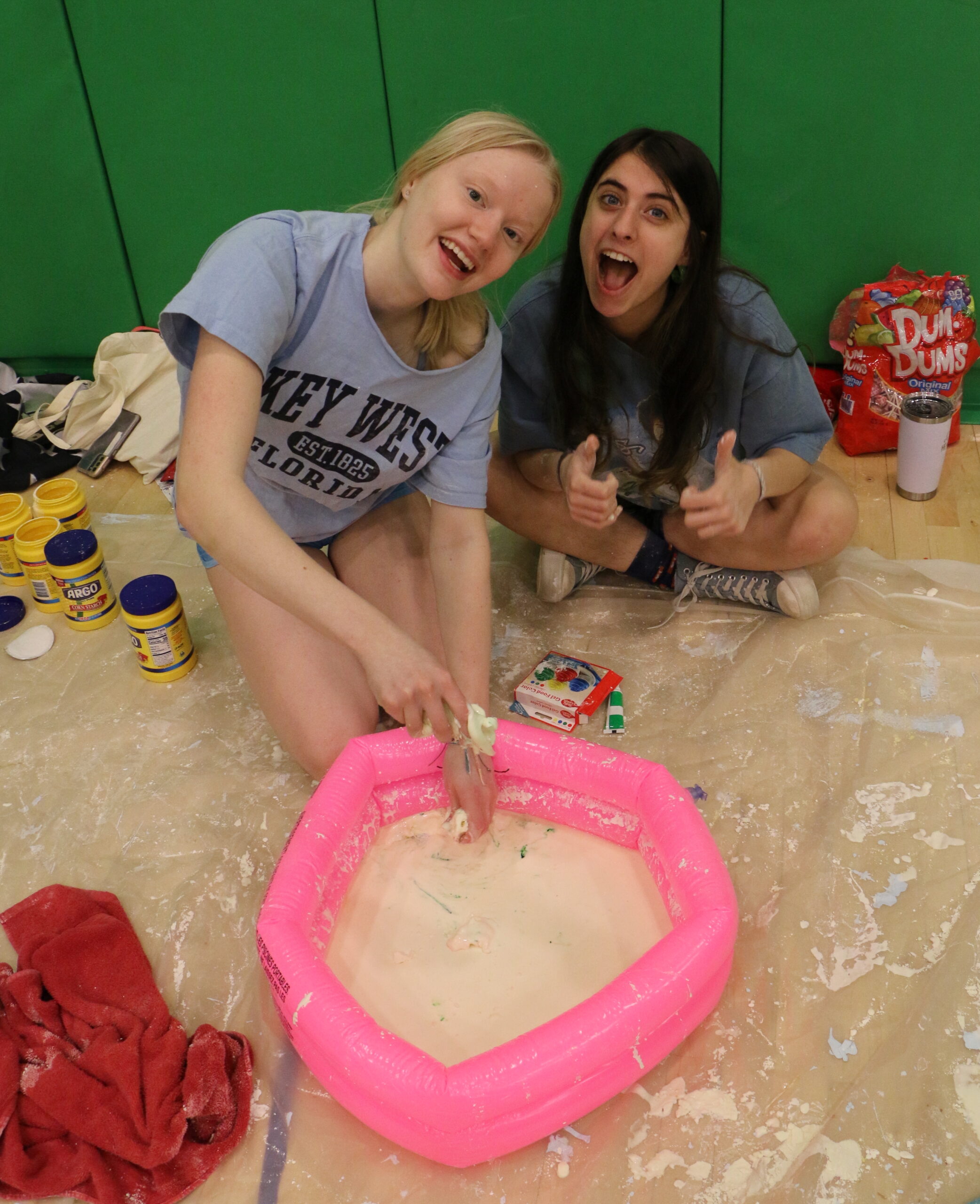 Students handling oobleck while smiling at camera
