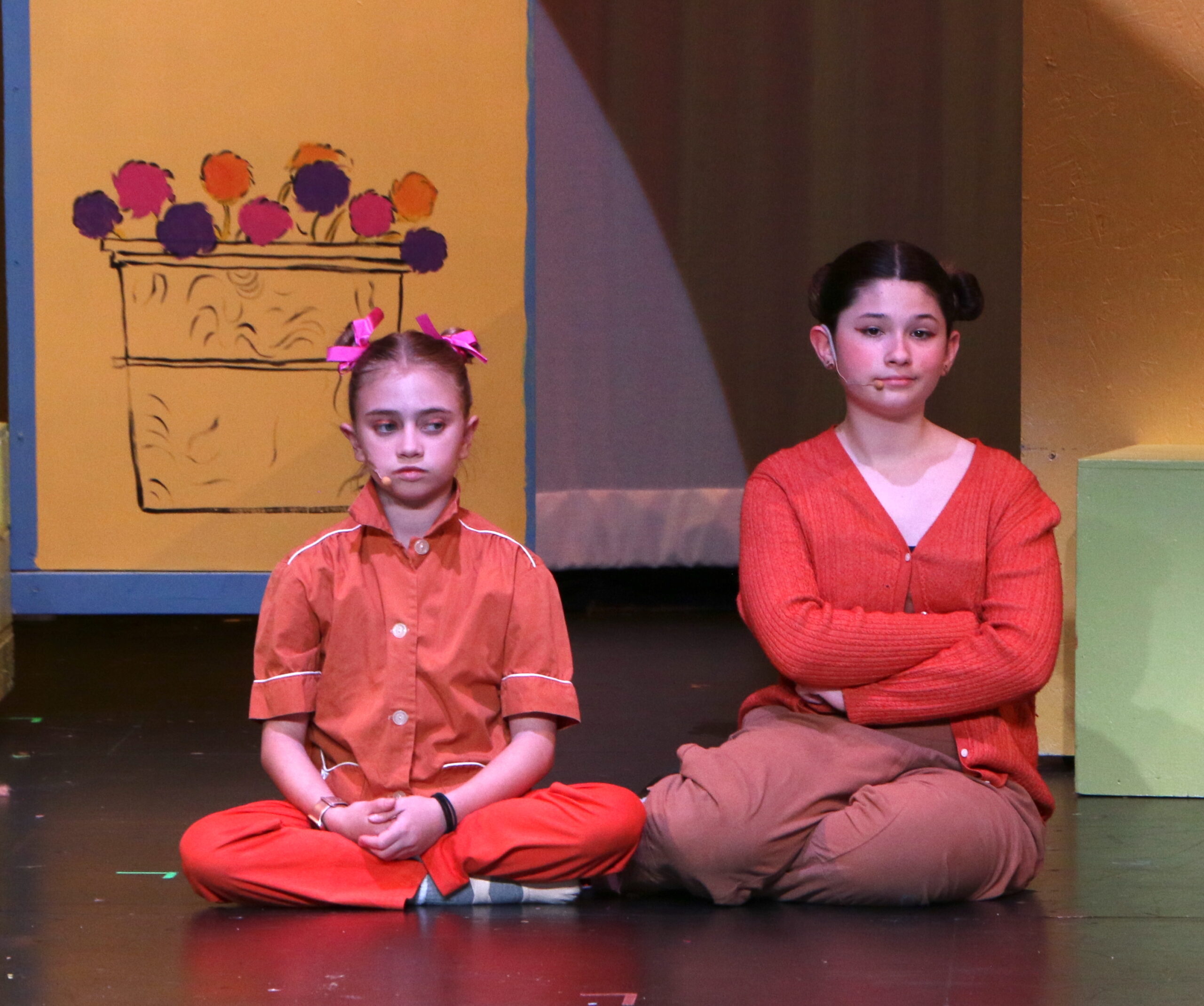 Two students performing on stage - sitting crossed legged and armed