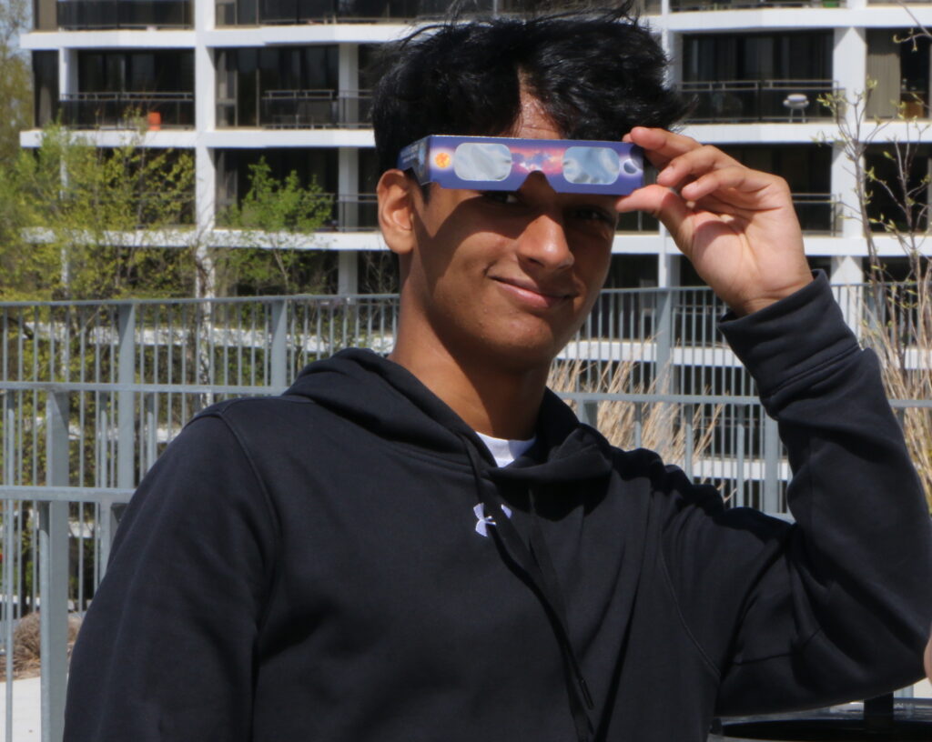 Student with eclipse glasses looking at the camera
