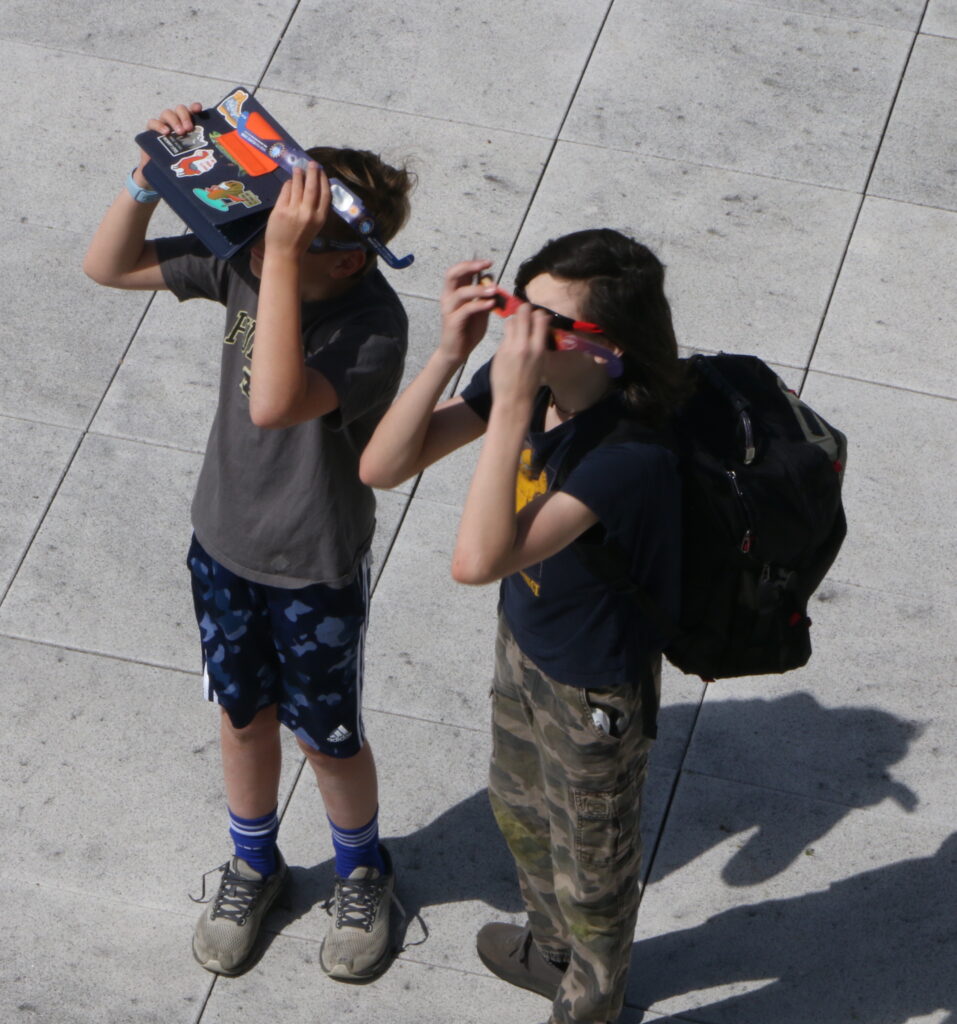 Two students viewing the eclipse with safety glasses