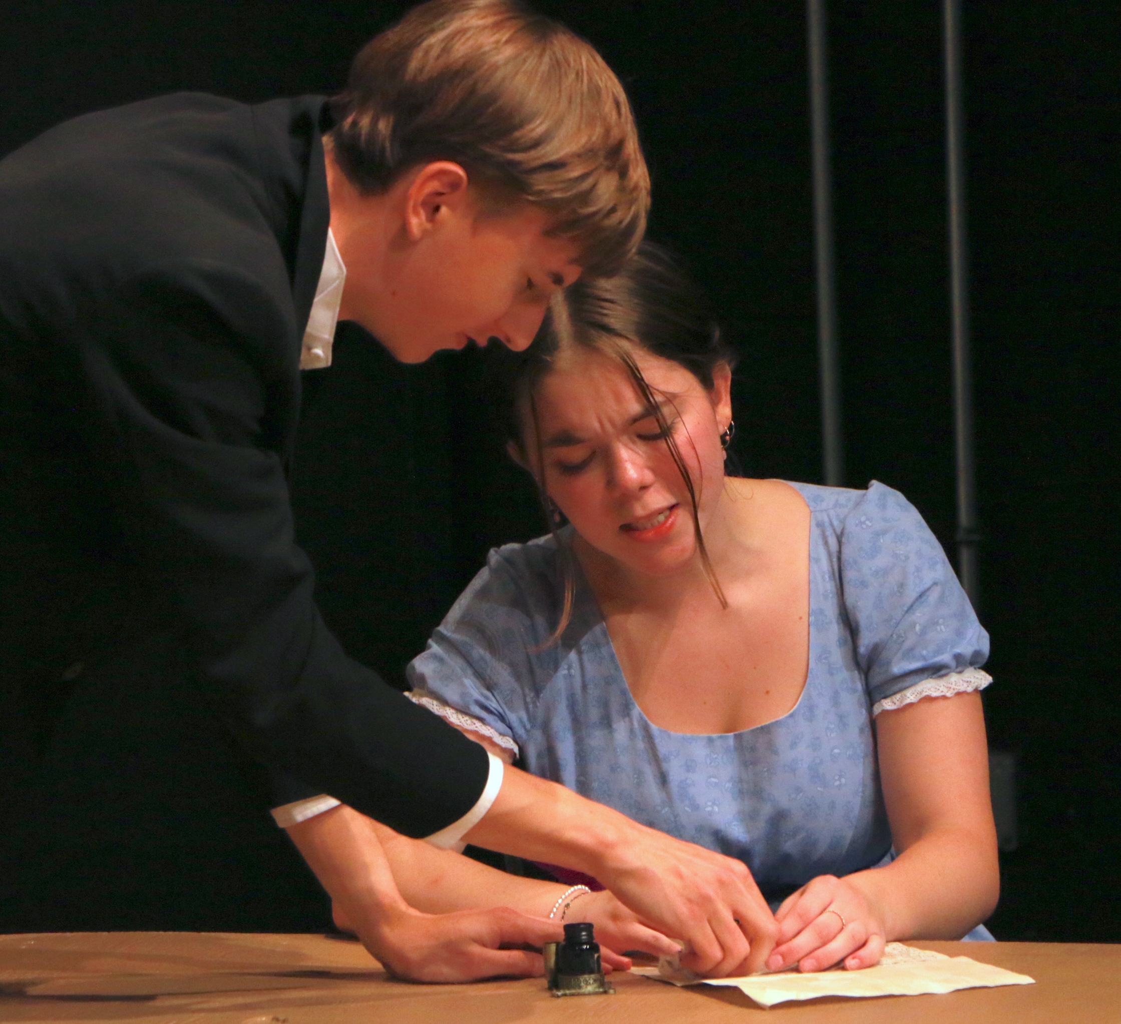 Woman signing a paper, while a man is pointing to someone on the paper