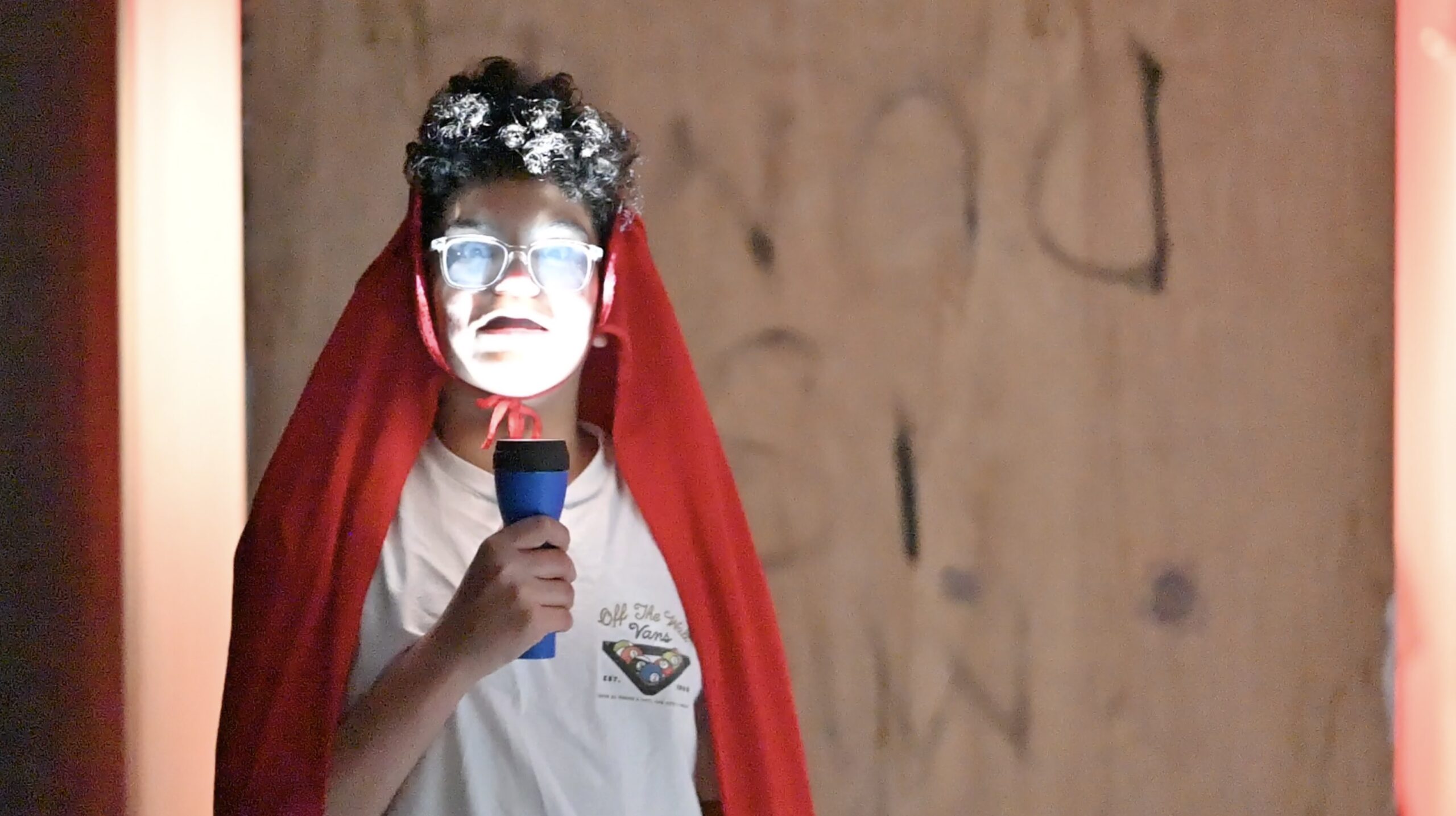 Student holding flashlight up to his face