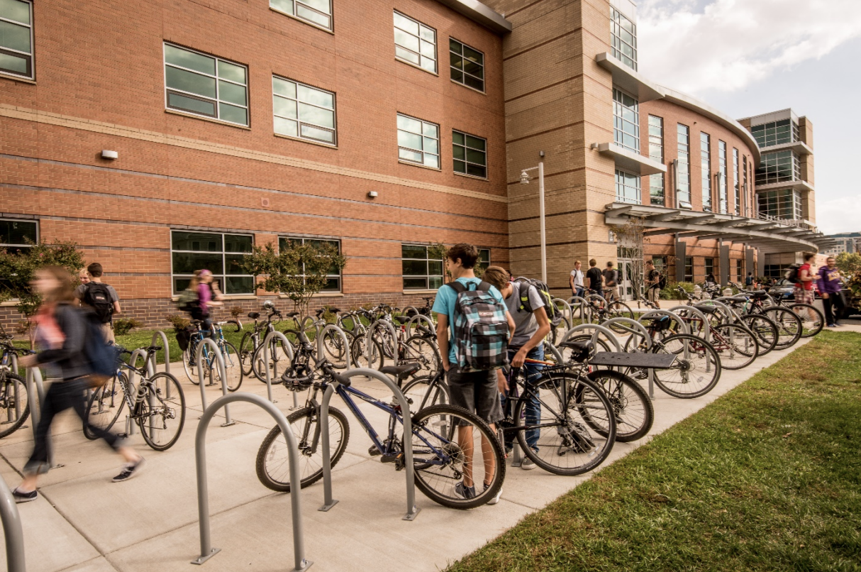 Students locking bikes to the rack in front of a school