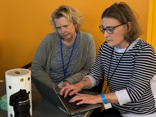 Parent volunteers looking at and typing on a laptop