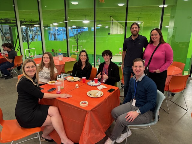 A group of parents and students sitting at table and smiling at the camera